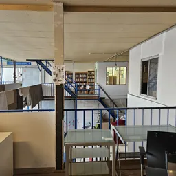 Bovenaanzicht van de winkelvloer met trappen, leuningen, boekenkasten en verschillende afdelingen in een tweelaagse kringloop
