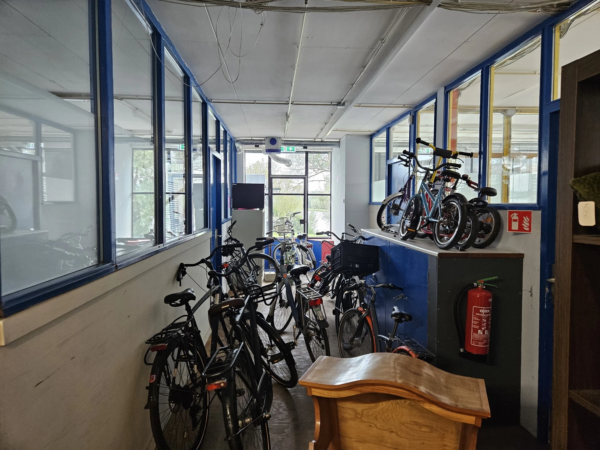 Fietsenstalling in een kringloopwinkel met meerdere tweedehands fietsen tegen de muur en op standaarden