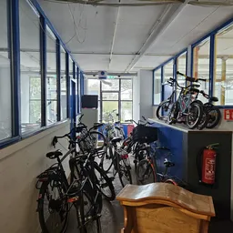 Fietsenstalling in een kringloopwinkel met meerdere tweedehands fietsen tegen de muur en op standaarden