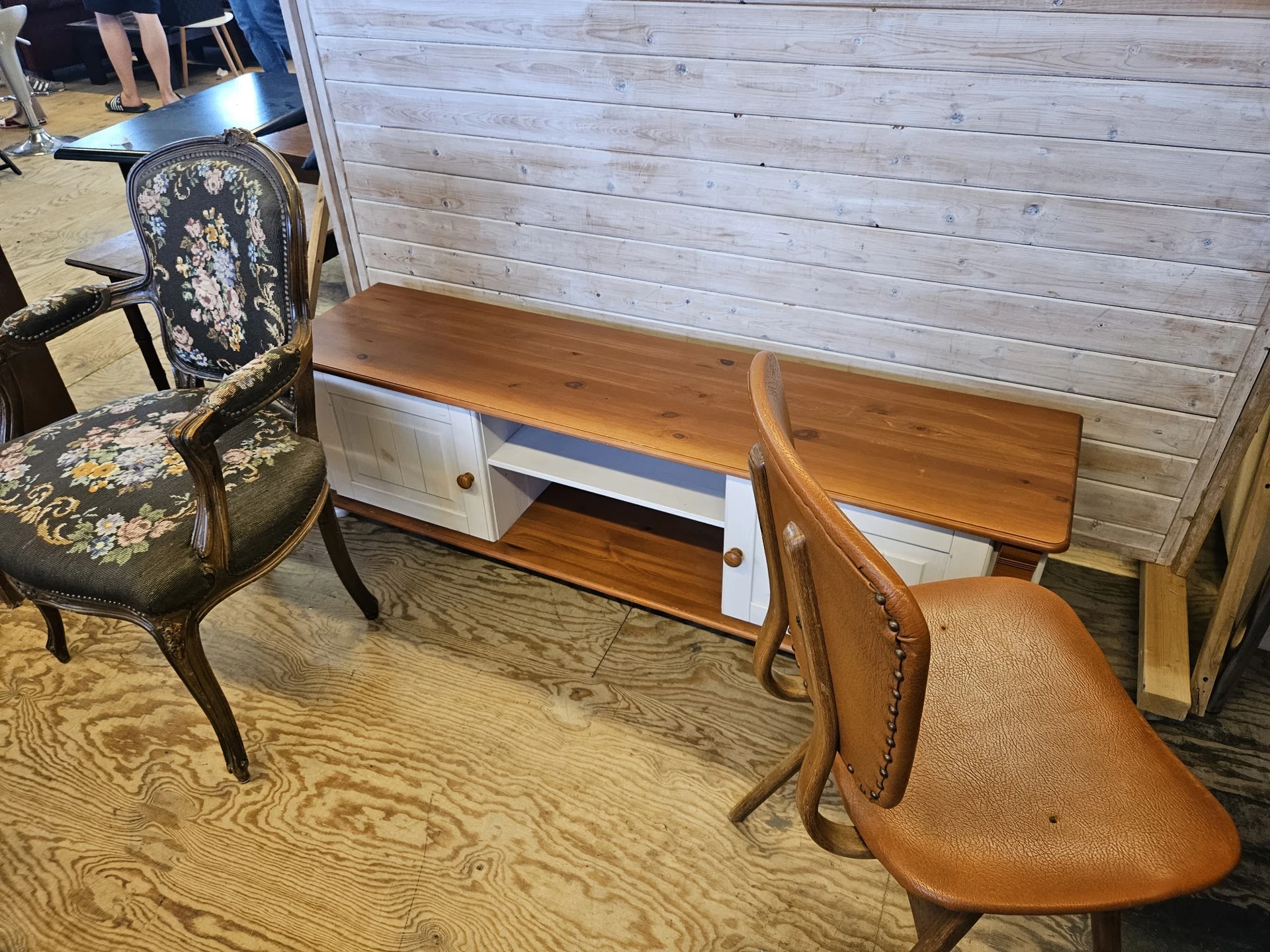 Tweedehands meubels: een bureau met witte laden, een bruine lederen stoel en een klassieke stoel met bloemmotief