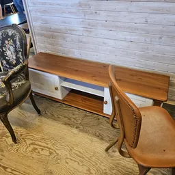 Tweedehands meubels: een bureau met witte laden, een bruine lederen stoel en een klassieke stoel met bloemmotief