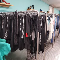 Rekken met tweedehands dameskleding in verschillende kleuren en patronen