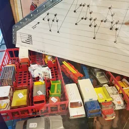Rode kunststof kratten met tweedehands auto-onderdelen en accessoires in een kringloopwinkel