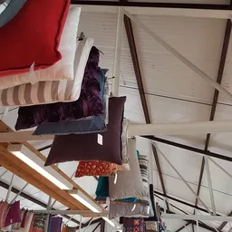 Verschillende kussens en textielartikelen opgehangen aan draad in het magazijn
