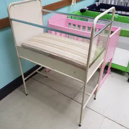 Tweepersoonsbed met metalen frame en houten slattenbodem in een kringloopwinkel