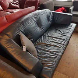 Zwarte lederen fauteuil met grijze kussens, schuin gefotografeerd vanaf bovenkant