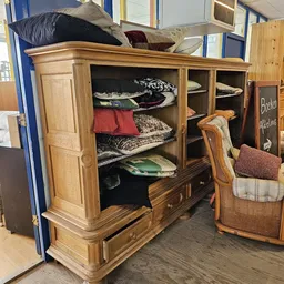 Houten vitrinekast met glasedeuren vol geordende textiel en beddengoed