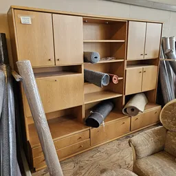 Tweedehandsmeubels in de winkel: houten kasten, gestoffeerde stoelen en opgerolde tapijten