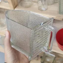 Close-up van een glazen voorraadpot met fijnmazig roestvrij stalen deksel in iemands hand