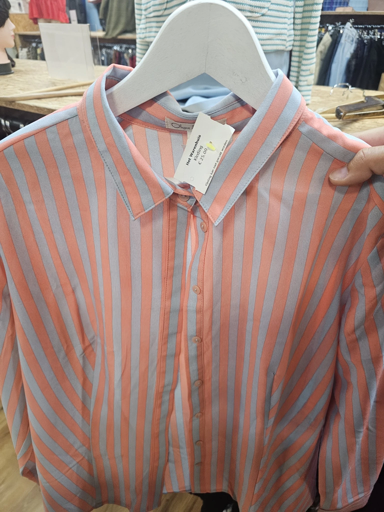 Close-up van een rood-wit gestreept herenkostuum met label aan de hanger
