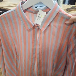 Close-up van een rood-wit gestreept herenkostuum met label aan de hanger