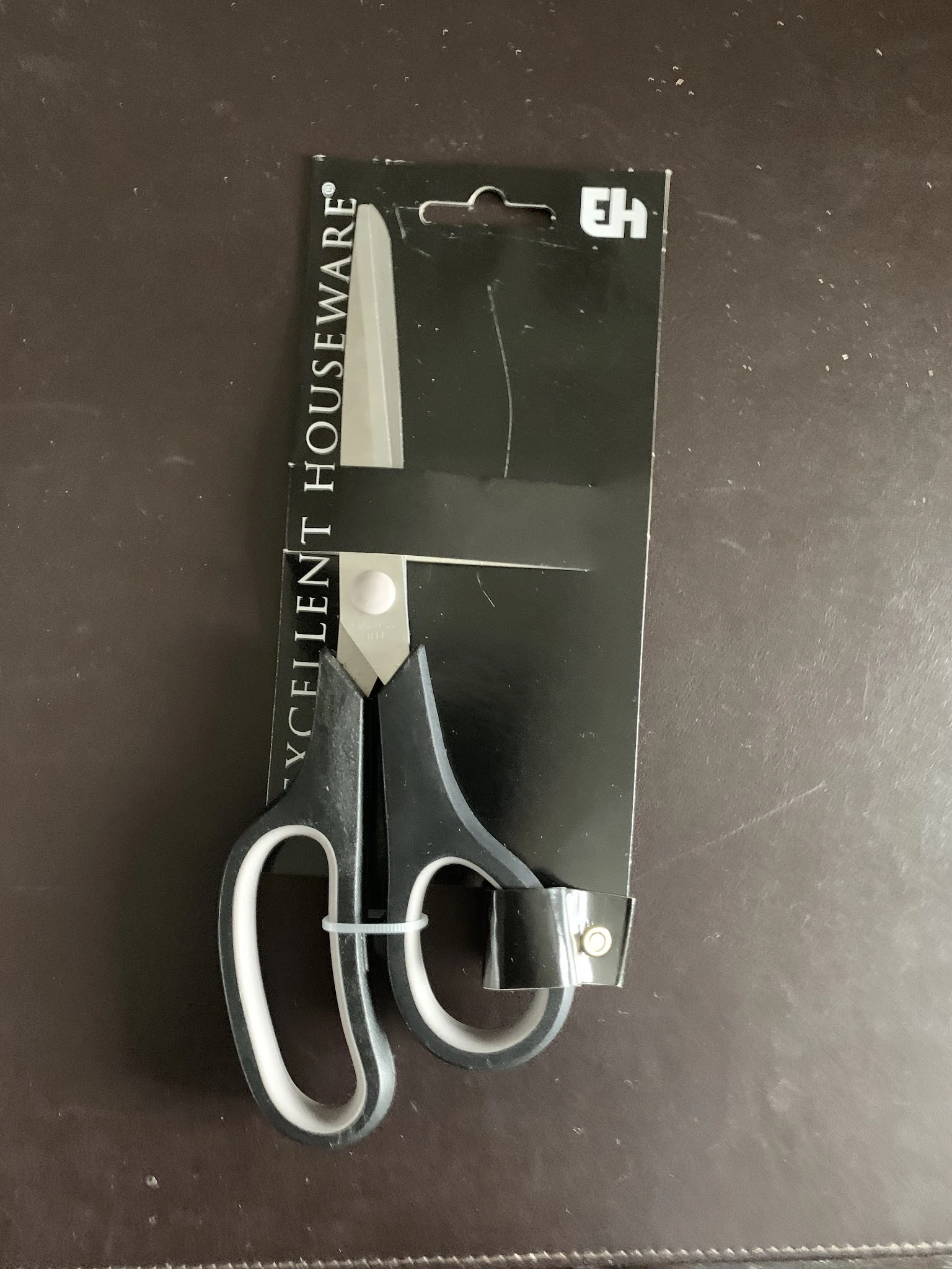 Close-up van een schaar met zwarte handvaten en zilveren bladen op verpakking