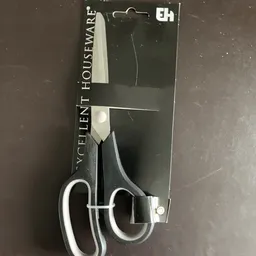 Close-up van een schaar met zwarte handvaten en zilveren bladen op verpakking