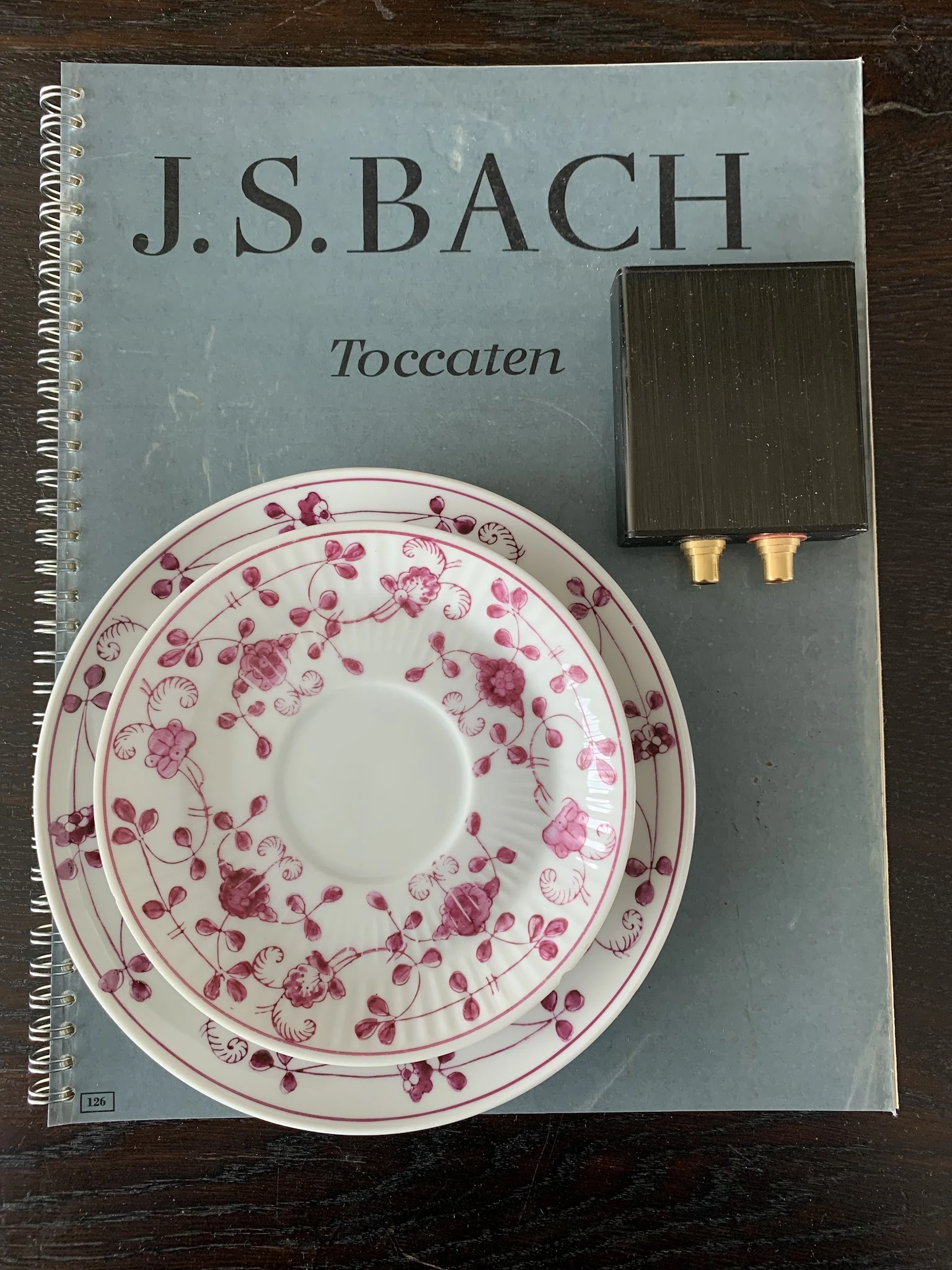Decoratief bord met roze bloemenpatroon, naast een spiraalschrift en ander object