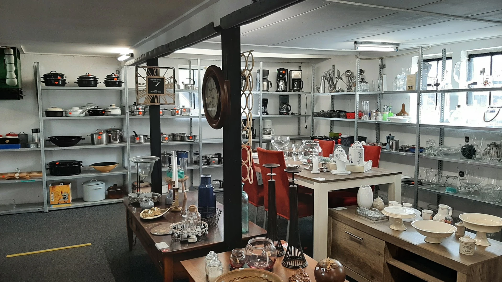 Interieur van kringloopwinkel met metalen stellingen vol servies, glazen, decoratie en huishoudelijke spullen