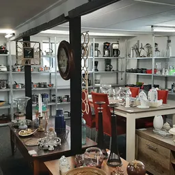 Interieur van kringloopwinkel met metalen stellingen vol servies, glazen, decoratie en huishoudelijke spullen
