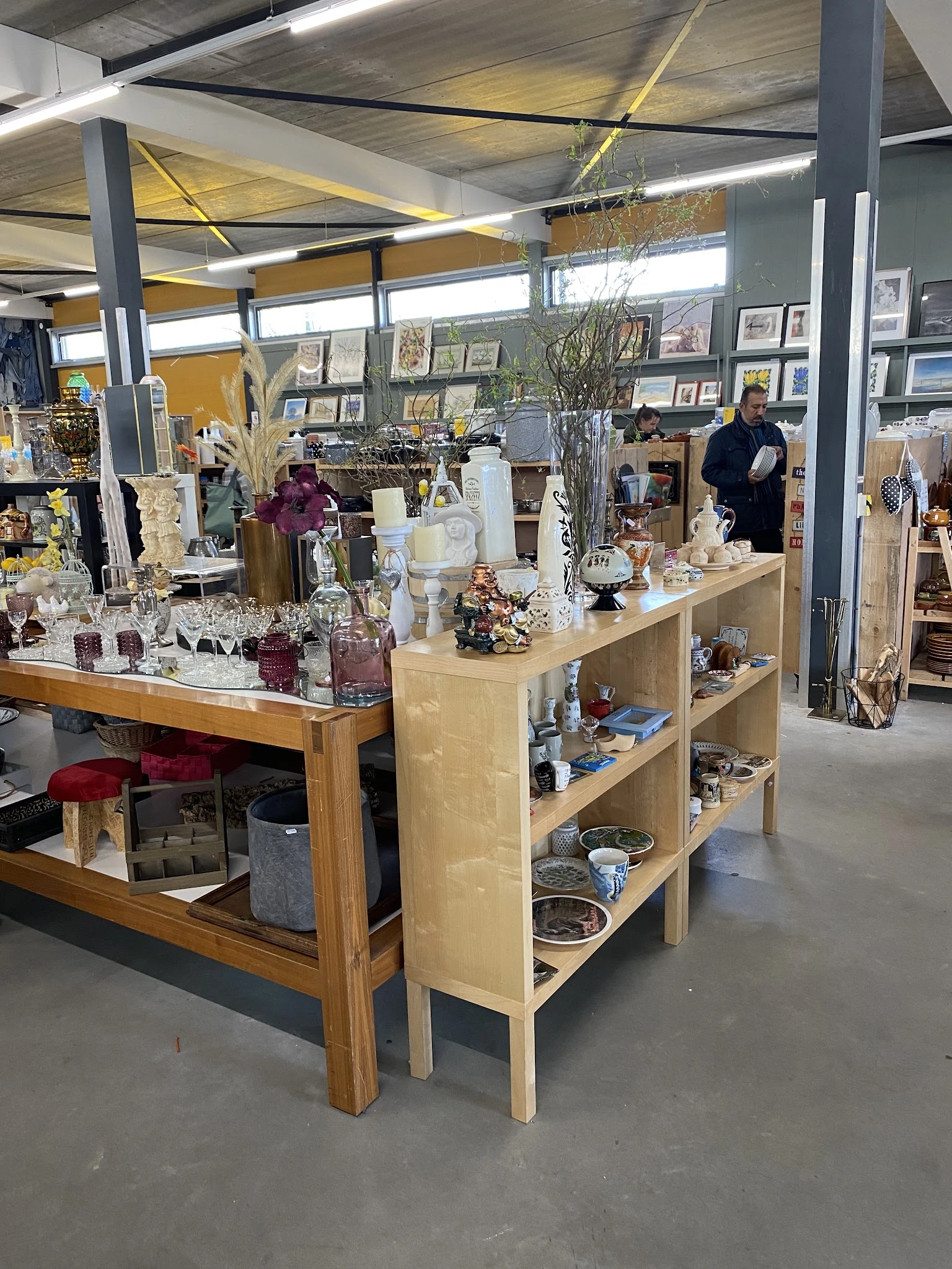 Uitgestalde decoratieve artikelen, vazen, kaarsen en huisraadgoederen op houten toonbank en open stellingen