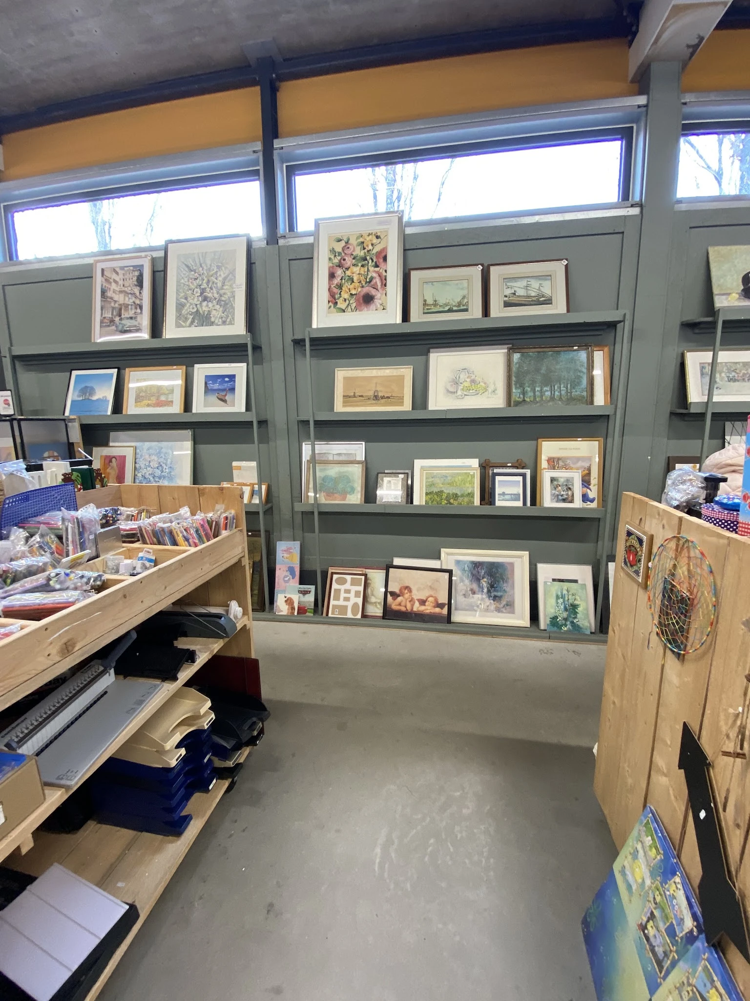 Stellingwand met uitgestalde kunstprenten, schilderijen en tekeningen in verschillende formats en stijlen
