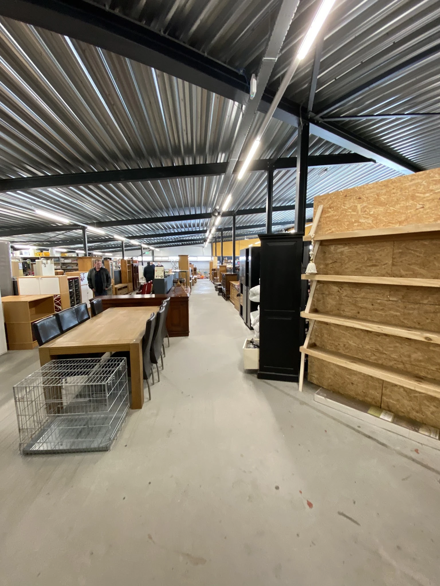 Winkelvloer met houten meubels, stellingen en diversen huisraad in een kringloopwinkel