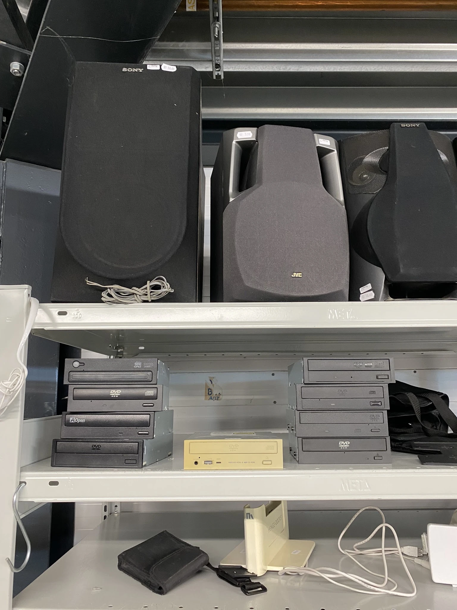Shelves with used electronic equipment including DVD players, speakers and computer components