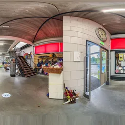 Panoramisch overzicht van het interieur van een kringloopwinkel met trap, stellingen, toonbank en rode signage