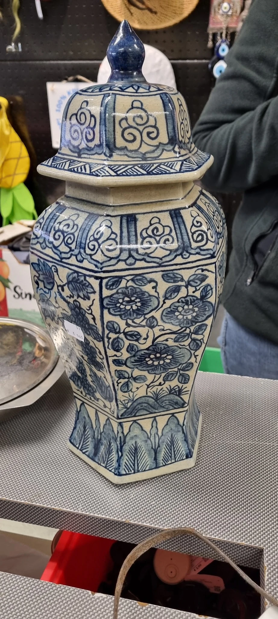 Blauwe met wit beschilderde vaas met bloemenmotieven en decoratieve rand.