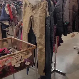 Tweedehands kleding op hangers en in bakken, met jassen, broeken en andere kledingstukken in verschillende kleuren