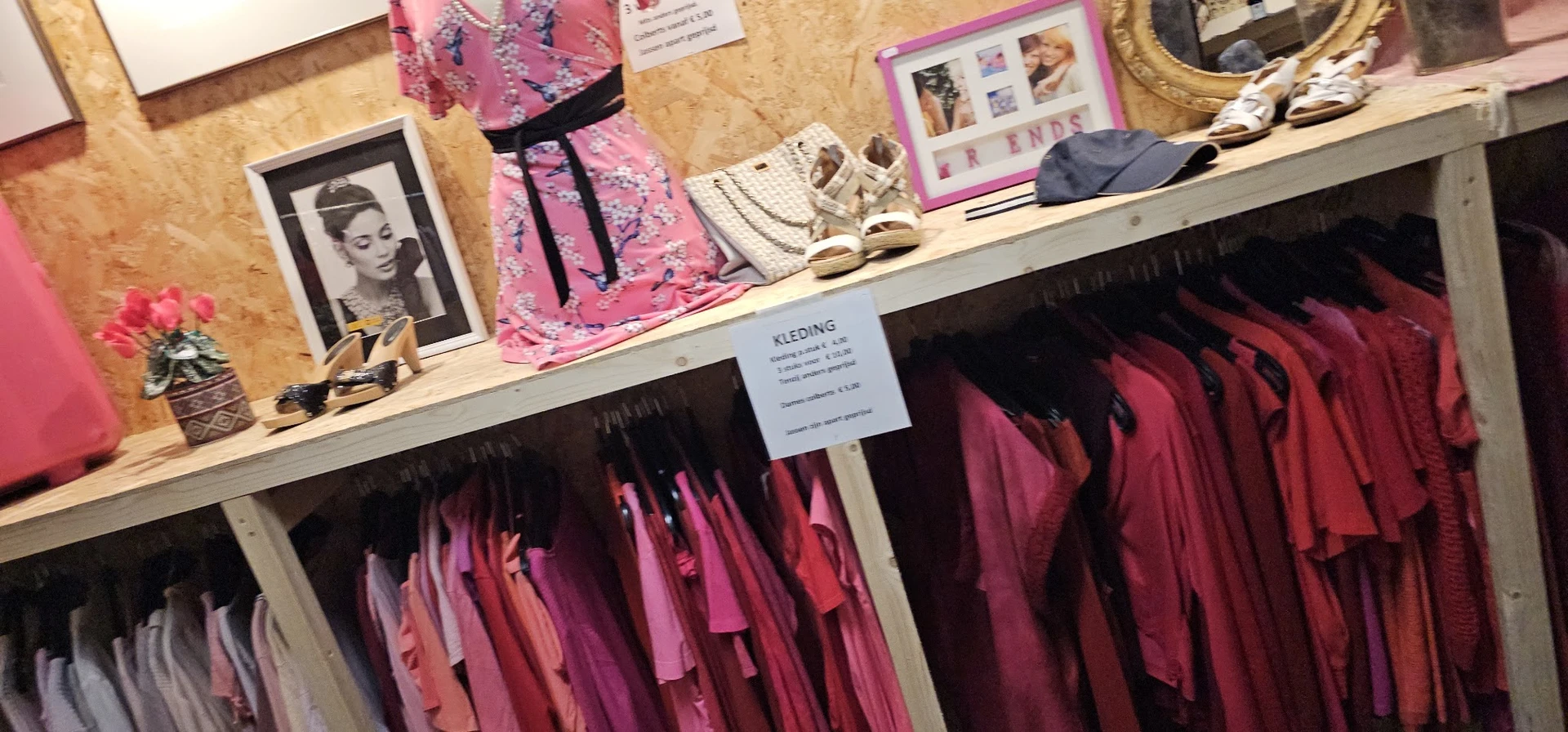 Winkelrek met roze en bordeauxrode jurken en accessoires, decoraties op plank boven