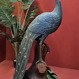 Blauw decoratief vogelfiguur met lange staart en groene bladeren tegen rode achtergrond