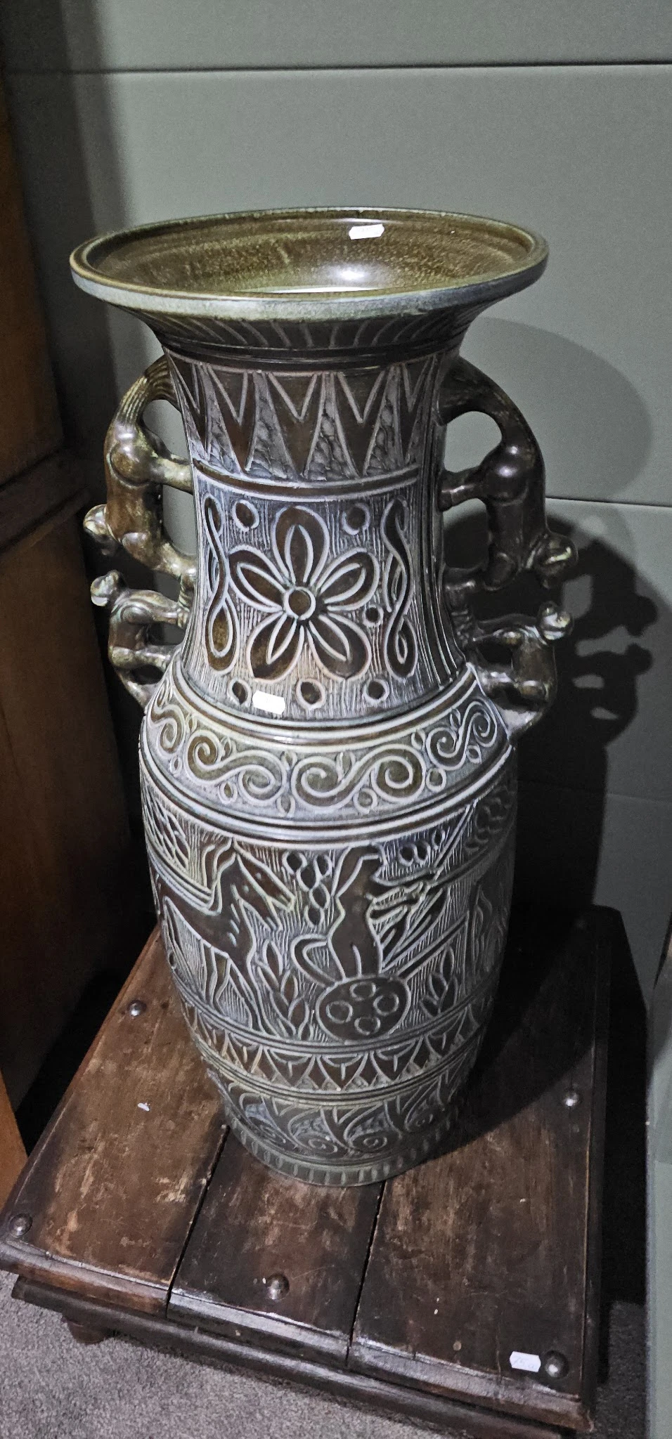 Close-up van een decoratieve vaas met wit en zwart reliëfwerk en dierenfiguren als hengsels