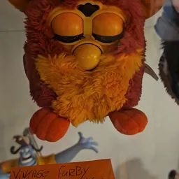 Furby-speelgoed met oranje en rood pluche, gesloten ogen en oranje poten