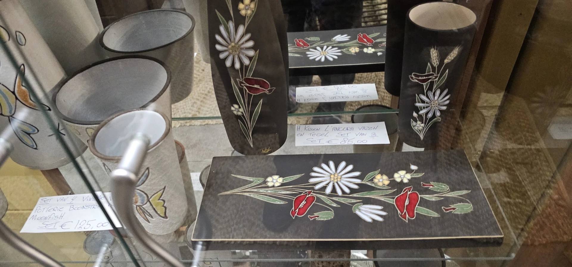 Zwarte serviesset met wit en rood bloemenpatroon, bestaande uit borden, kopjes en schalen