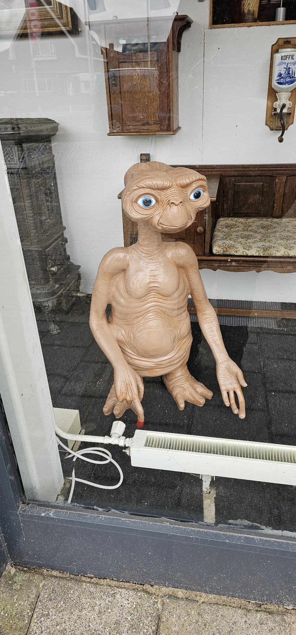 Houten sculptuur van een mannelijk figuur met anatomische details, zittend in een kringloopwinkel