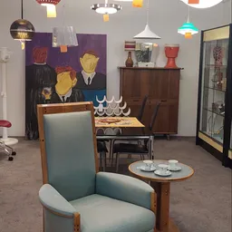 Winkelvloer met vintage meubels, kunstwerk en servies op display in kringloopwinkel