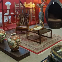 Winkelinterieur met bruine lederen fauteuil, salontafel, Aziatische decorstukken en rode vloerbedekking