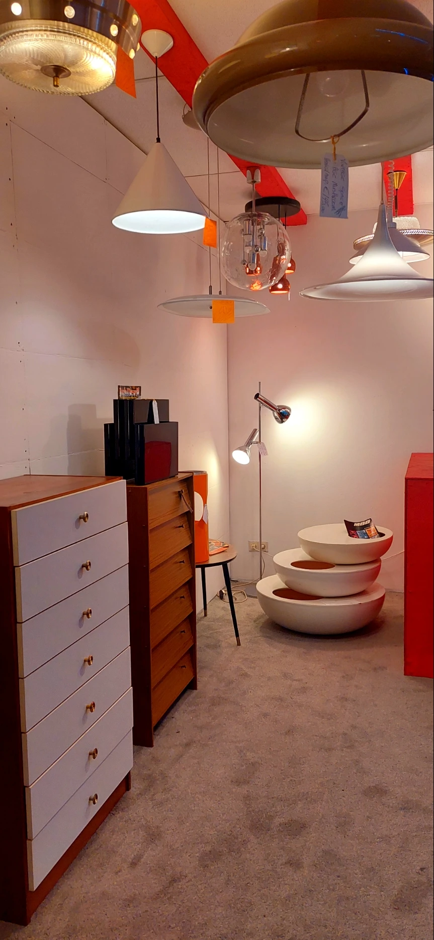 Uitgestalde serviesgoed en huishoudartikelen in de winkel, met stapels witte schalen en diverse meubels op de achtergrond