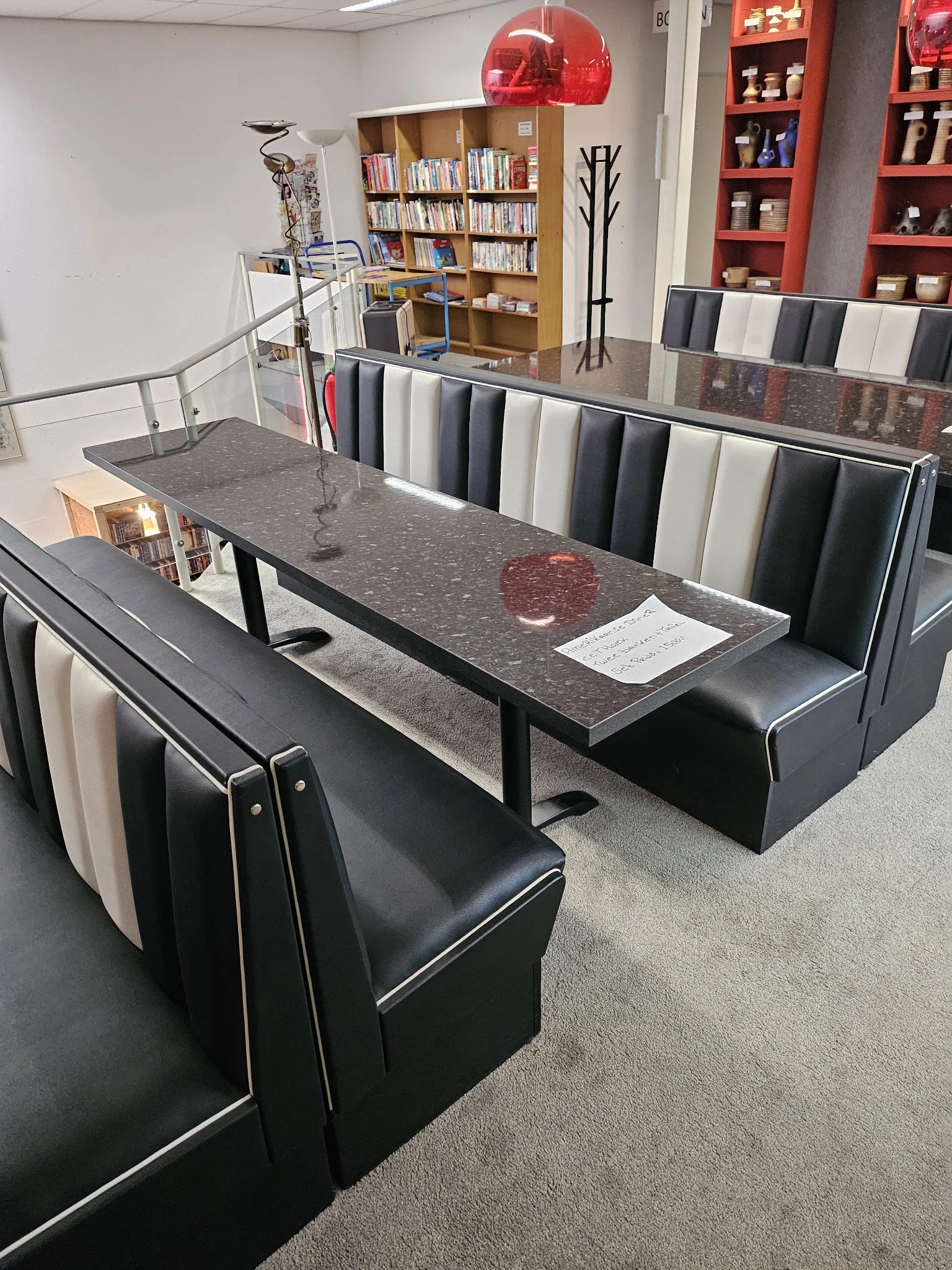 Uitgestalde stoffen en materialen op tafel en in rekken, met grijs granito blad en zwarte zitbank