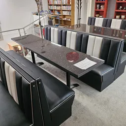 Uitgestalde stoffen en materialen op tafel en in rekken, met grijs granito blad en zwarte zitbank
