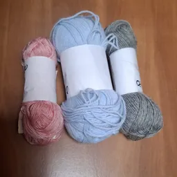 Drie bollen breiwol in roze, lichtblauw en grijs met witte bandjes