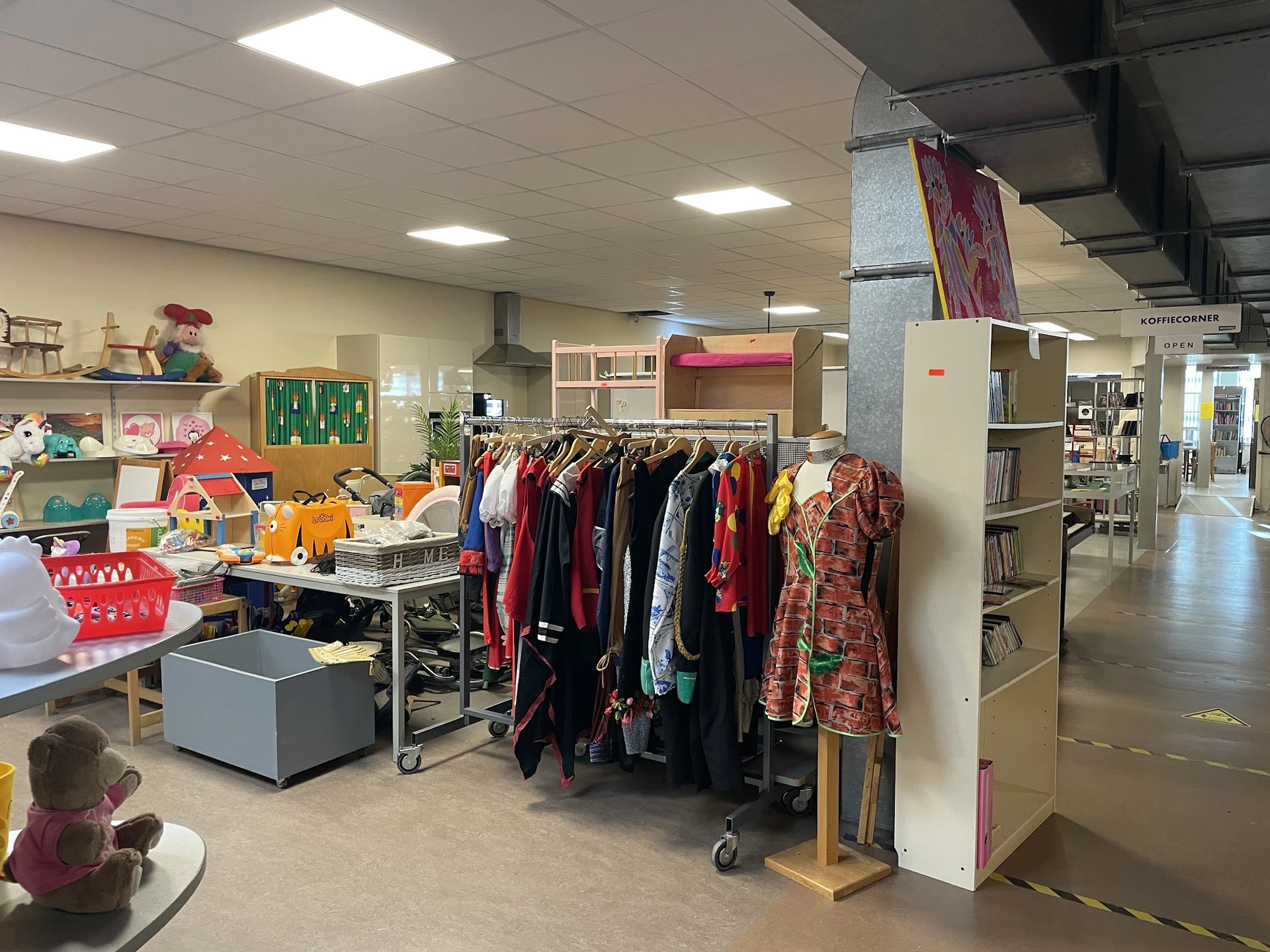 Winkelinterieur met kledingrekken, speelgoed, boekenkasten en diverse tweedehands spullen