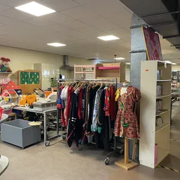Winkelinterieur met kledingrekken, speelgoed, boekenkasten en diverse tweedehands spullen