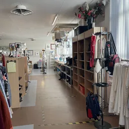 Winkelinterieur met kledingrekken, stellingen met textiel en diverse tweedehands artikelen