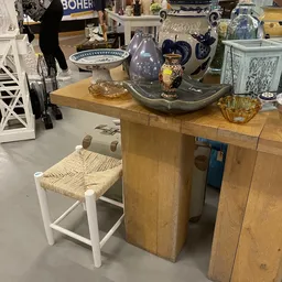 Houten tafels en stoelen met decoratieve items zoals serviesgoed en vazen op het blad
