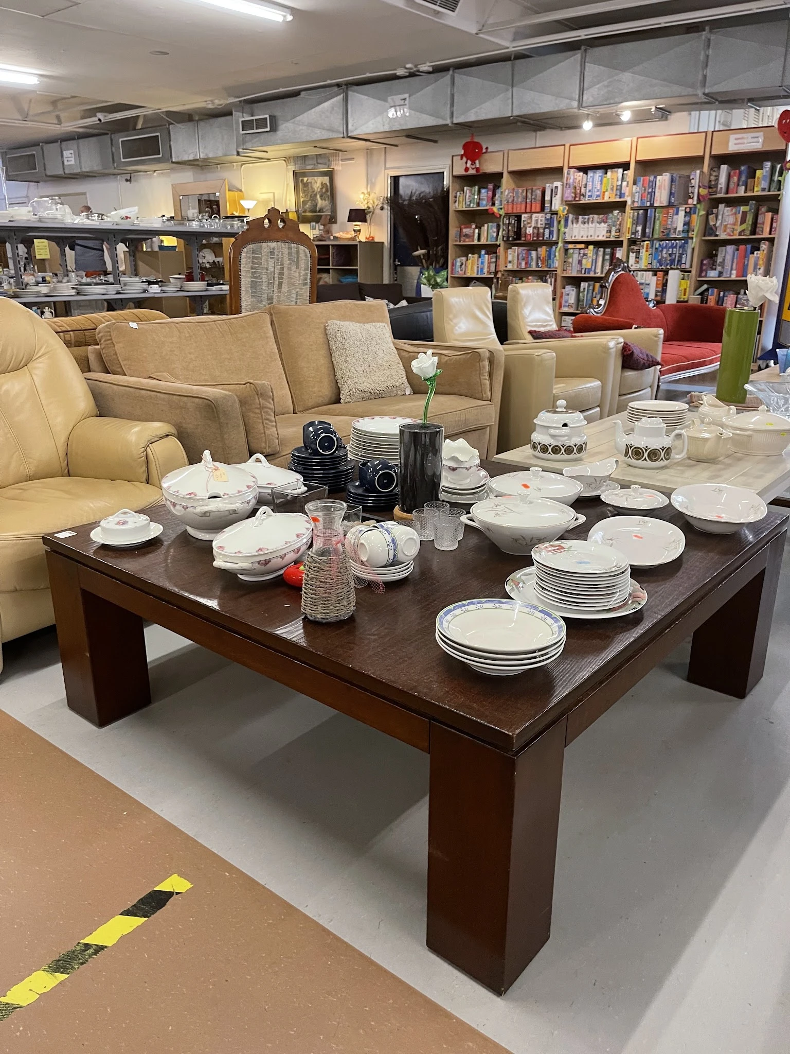 Bruine salontafel met wit serviesgoed, glazen en decoratie, naast beige stoelen