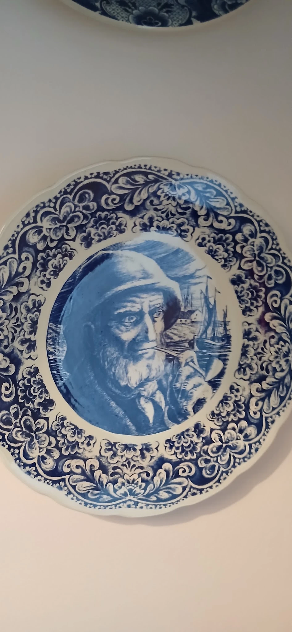 Decoratief blauw-wit porseleinbord met randversiering en portret van een bebaarde man in het centrum