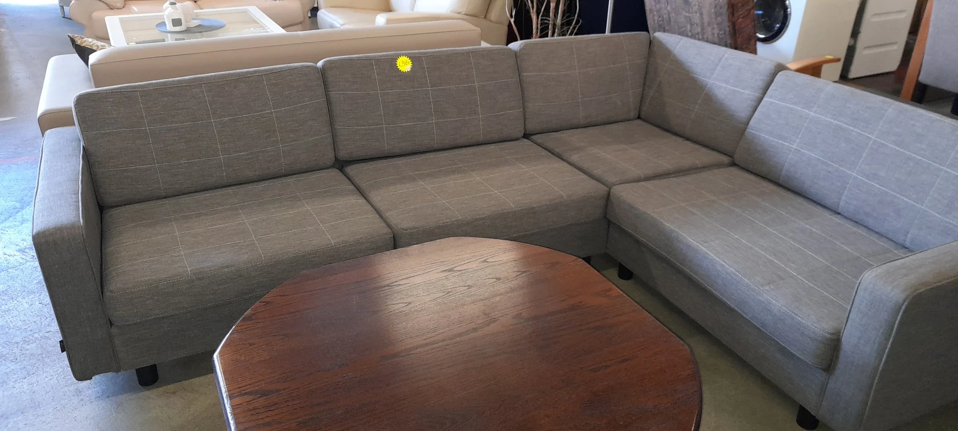 Grijze hoekbank met houten salontafel in uitstalkamer van kringloopwinkel