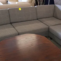 Grijze hoekbank met houten salontafel in uitstalkamer van kringloopwinkel