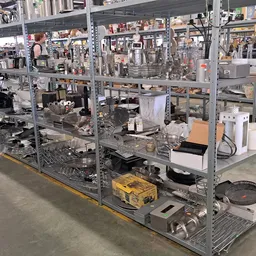Metalen stellingen met verzameling huishoudelijke spullen, pannen, servies en apparaten in een kringloopwinkel