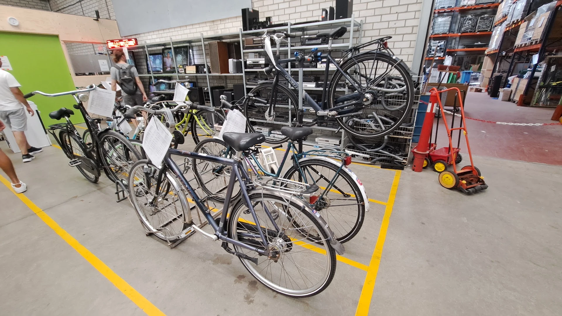 Tweedehands fietsen uitgestald in de winkel, met gele markeringen op de vloer