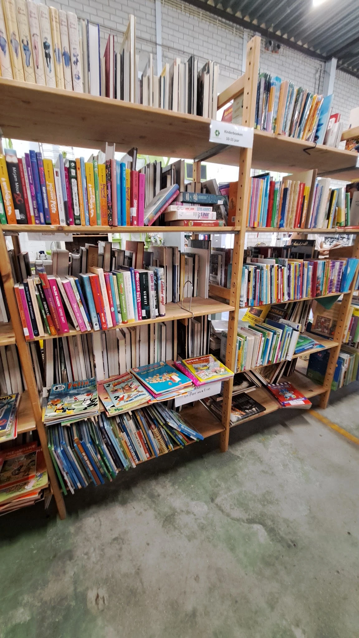 Houten stellingen met tweedehands boeken, dvd's en cd's netjes gerangschikt